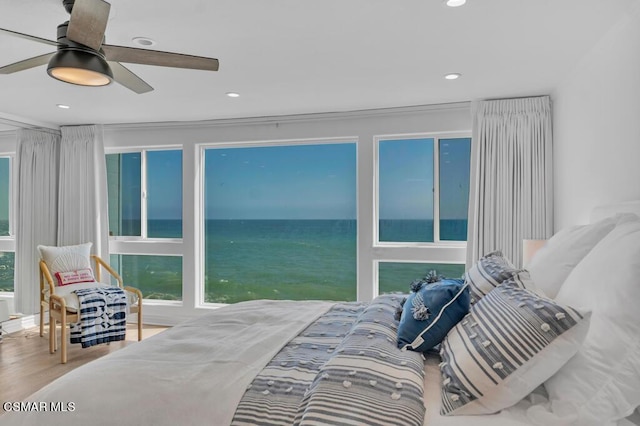 bedroom featuring ceiling fan, wood-type flooring, and a water view