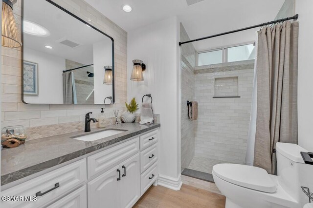 bathroom with toilet, a shower with shower curtain, tasteful backsplash, wood-type flooring, and vanity