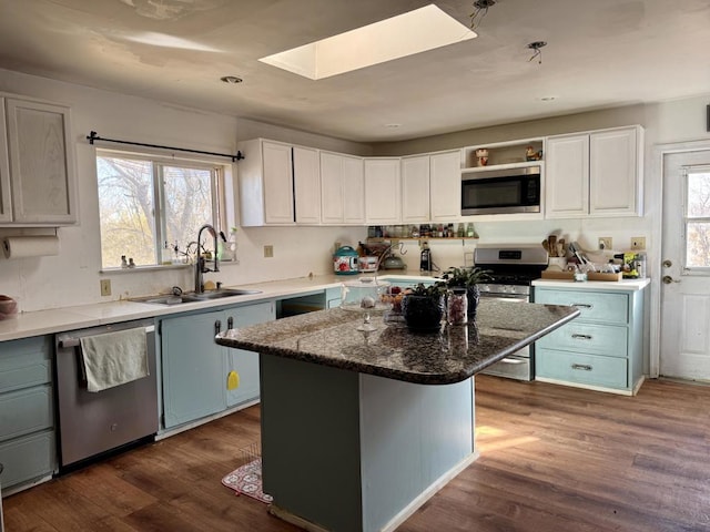 kitchen with white cabinets, sink, stainless steel appliances, and a center island