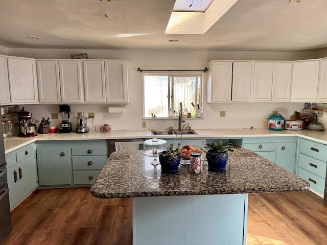 kitchen with a center island, sink, light wood-type flooring, a skylight, and white cabinets