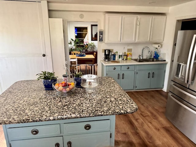 kitchen with a center island, stainless steel refrigerator with ice dispenser, sink, hardwood / wood-style flooring, and blue cabinets