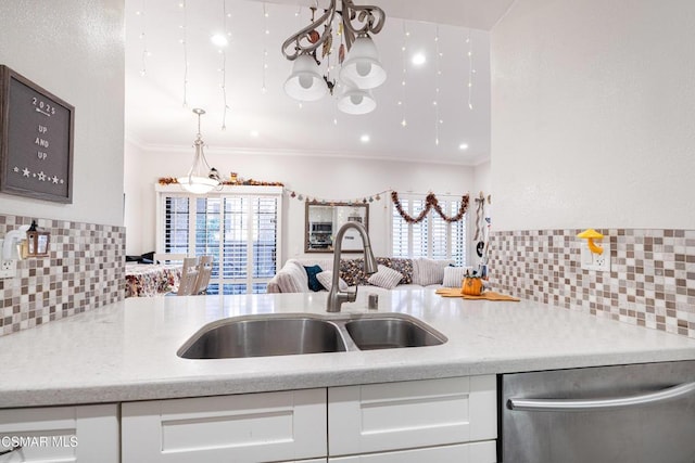 kitchen with light stone countertops, white cabinets, dishwasher, sink, and crown molding