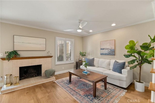 living room featuring ceiling fan, a fireplace, ornamental molding, and hardwood / wood-style floors