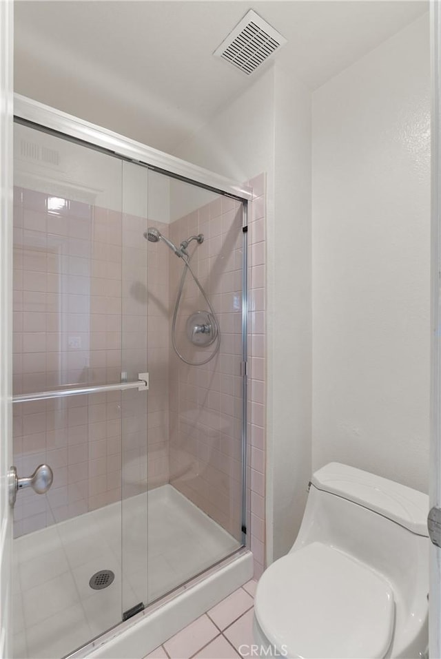 bathroom with toilet, tile patterned flooring, and a shower with shower door