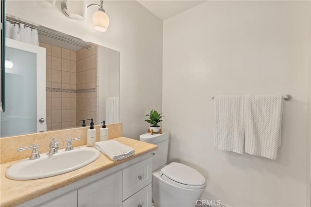 bathroom featuring toilet, a tile shower, and vanity