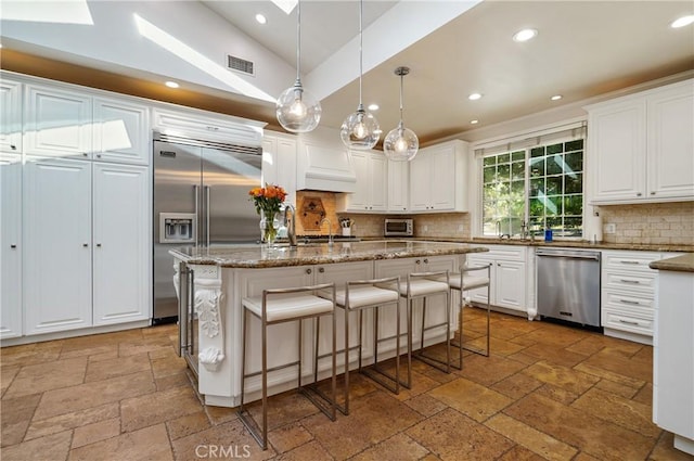 kitchen with stainless steel appliances, white cabinets, and stone tile floors