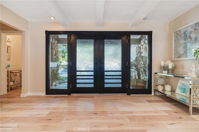 doorway featuring light wood-style floors, beam ceiling, and baseboards