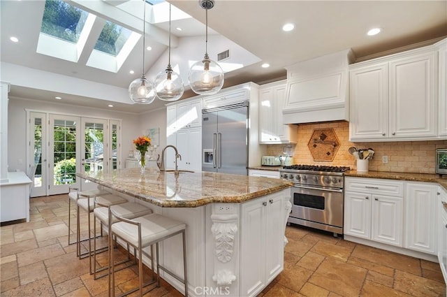 kitchen featuring white cabinetry, a center island with sink, and high end appliances