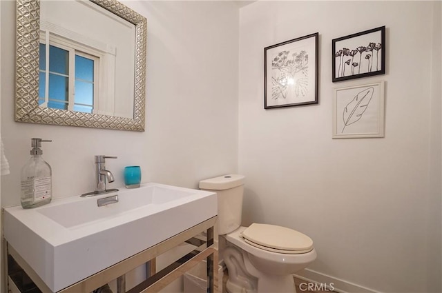 bathroom with vanity, toilet, and baseboards