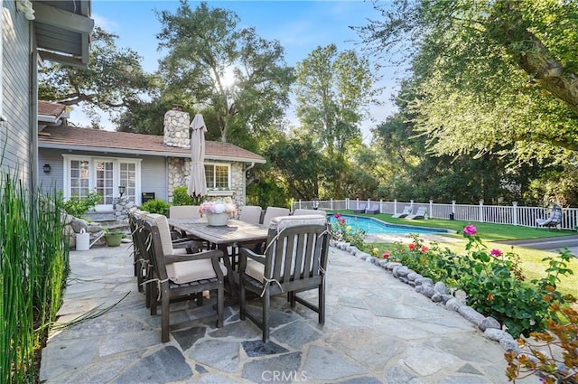 view of patio with outdoor dining space, fence, and a fenced in pool