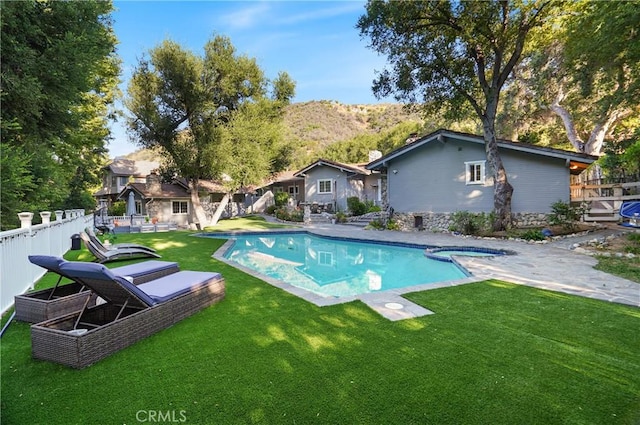 view of swimming pool with a mountain view, a pool with connected hot tub, fence, and a lawn