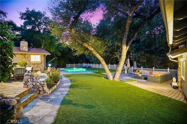 yard at dusk with an outdoor living space and a patio