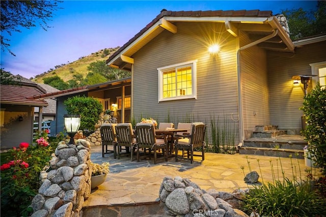 back of house at dusk featuring outdoor dining space and a patio area