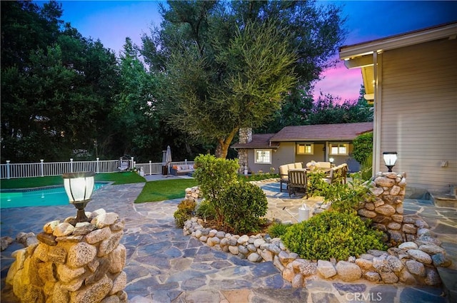 pool at dusk with a patio, fence, and an outdoor living space