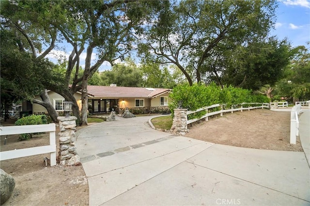 ranch-style house featuring stucco siding, a fenced front yard, and a tiled roof