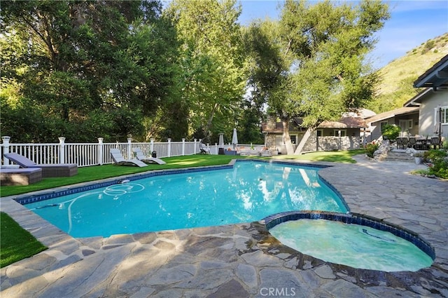 view of swimming pool with a pool with connected hot tub, fence, and a patio