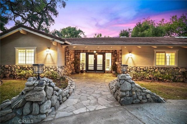 back of property with stone siding and french doors