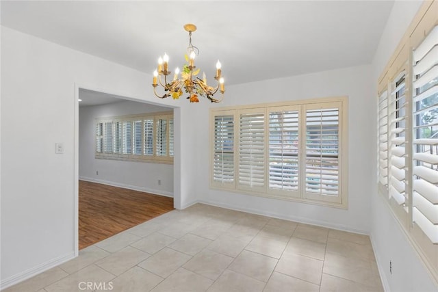 unfurnished dining area featuring light tile patterned floors and a notable chandelier