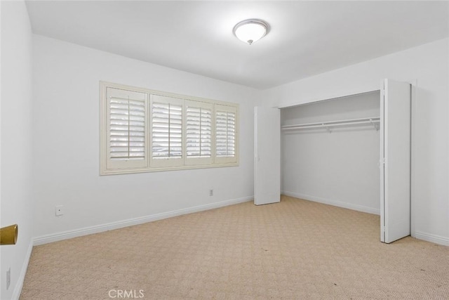 unfurnished bedroom featuring light carpet and a closet