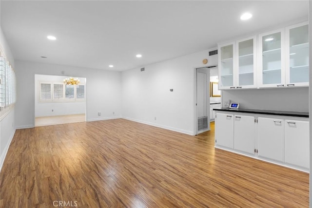 unfurnished living room with light hardwood / wood-style floors and a notable chandelier