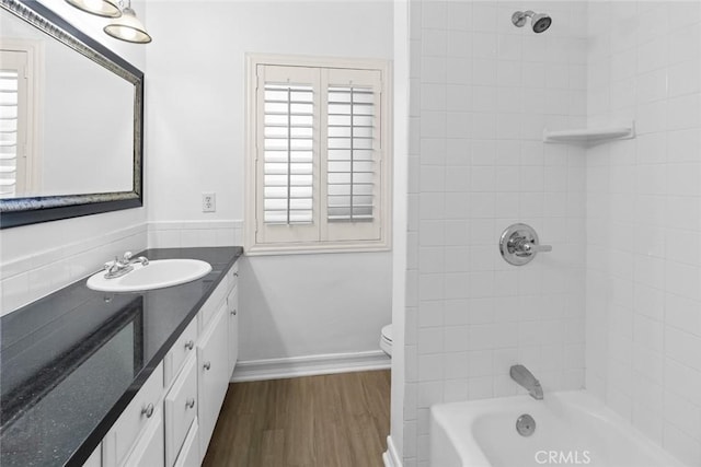 full bathroom with toilet, tiled shower / bath combo, hardwood / wood-style flooring, and vanity