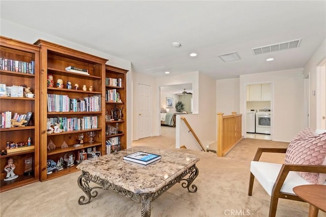 living area with washing machine and dryer, ceiling fan, and light colored carpet