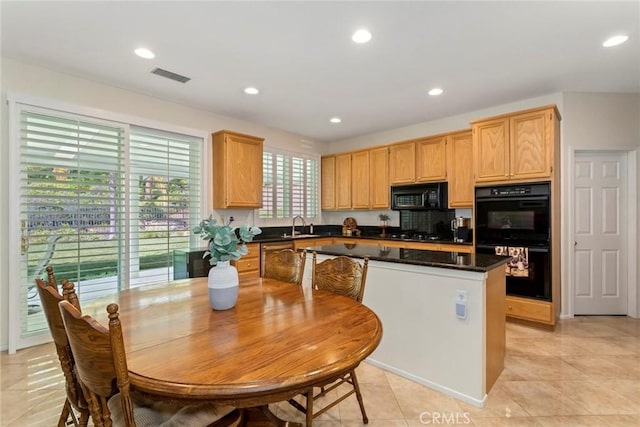 kitchen with a center island, black appliances, sink, light brown cabinets, and light tile patterned floors