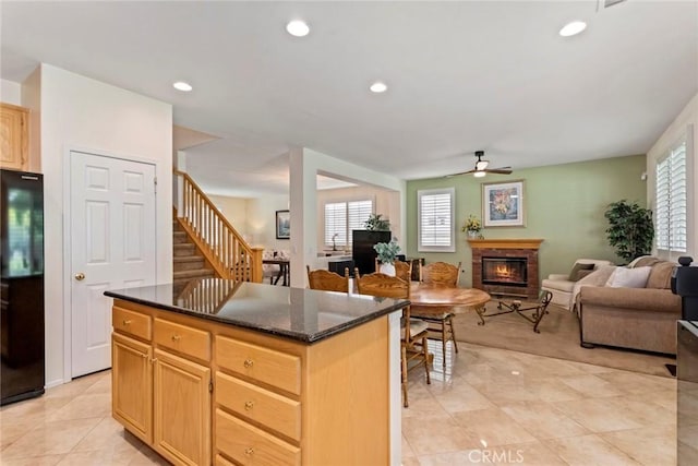 kitchen with black refrigerator, ceiling fan, a wealth of natural light, light brown cabinetry, and a kitchen island