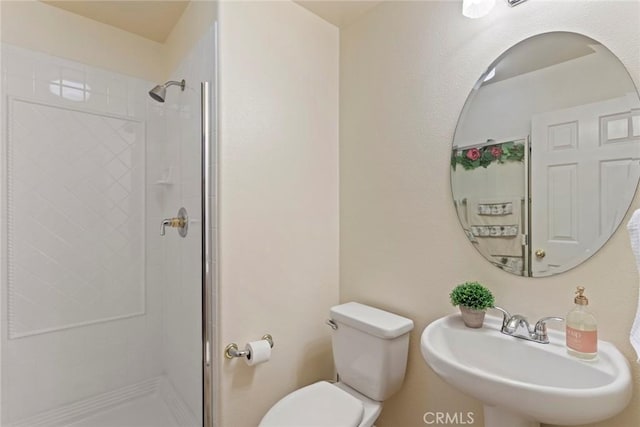 bathroom featuring toilet, a shower with shower door, and sink