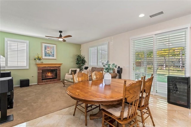 carpeted dining room with ceiling fan, beverage cooler, and a brick fireplace