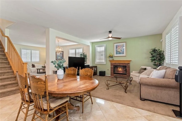 dining area with light tile patterned flooring, ceiling fan with notable chandelier, and plenty of natural light