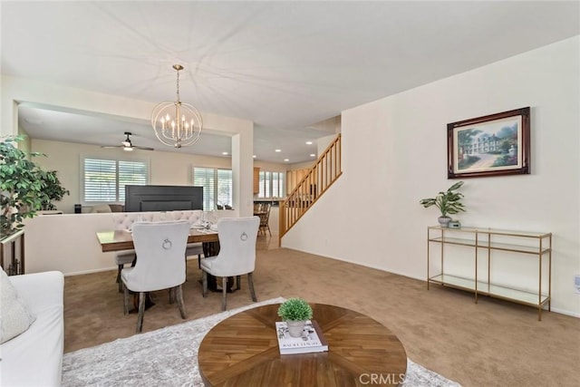 carpeted living room with ceiling fan with notable chandelier