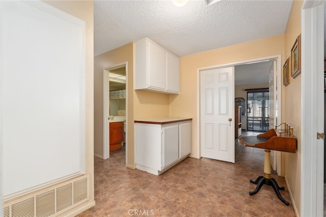 kitchen featuring white cabinets and a textured ceiling