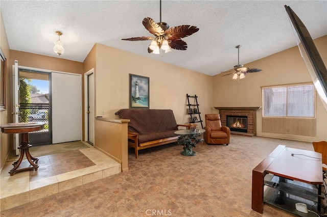 living room featuring ceiling fan, vaulted ceiling, a fireplace, and a textured ceiling