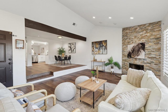 living room featuring hardwood / wood-style floors, a stone fireplace, and high vaulted ceiling