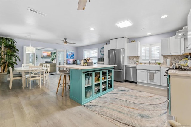 kitchen with white cabinetry, a breakfast bar, stainless steel appliances, and a kitchen island