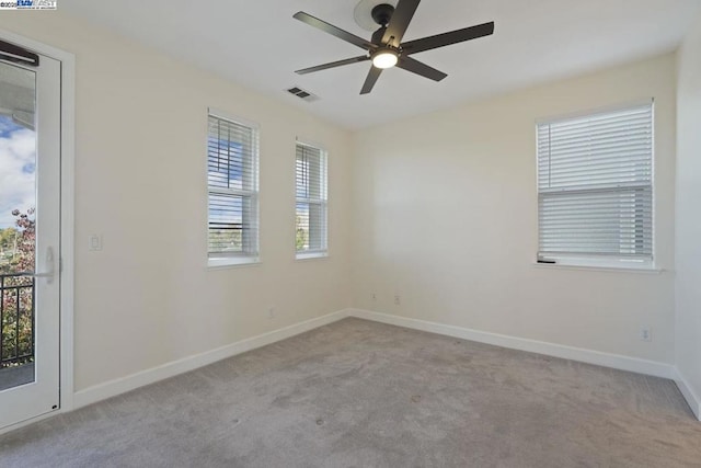 empty room with ceiling fan, light colored carpet, and plenty of natural light