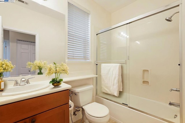 full bathroom with combined bath / shower with glass door, vanity, and toilet