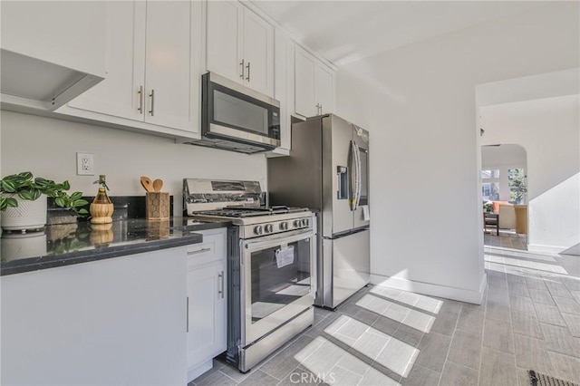 kitchen with white cabinets, stainless steel appliances, and dark stone counters