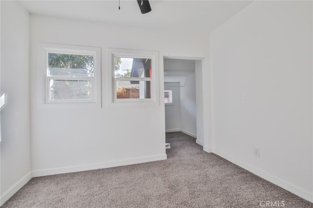 unfurnished room featuring ceiling fan, a wealth of natural light, and light carpet