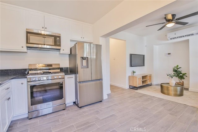 kitchen with ceiling fan, an AC wall unit, appliances with stainless steel finishes, and white cabinetry