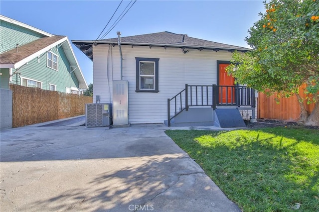 rear view of house with central AC, a yard, and a patio