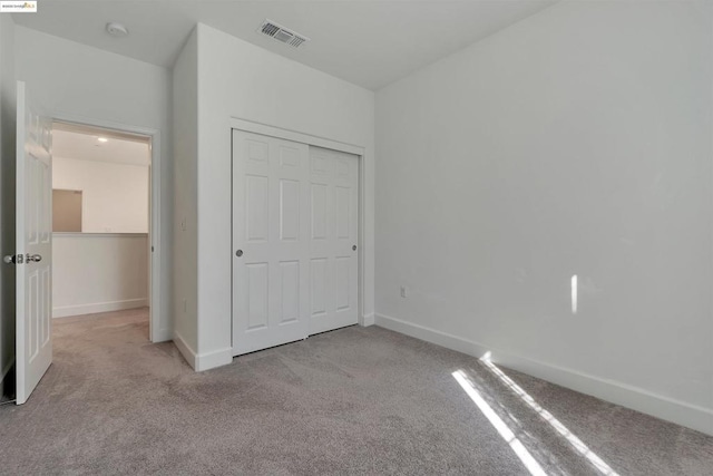 unfurnished bedroom with light colored carpet and a closet