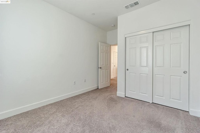 unfurnished bedroom featuring light colored carpet and a closet