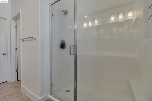 bathroom with a shower with shower door and tile patterned floors