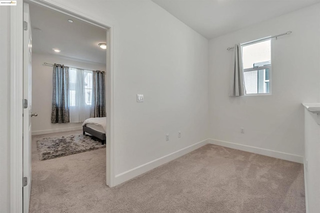 unfurnished bedroom with light colored carpet and multiple windows