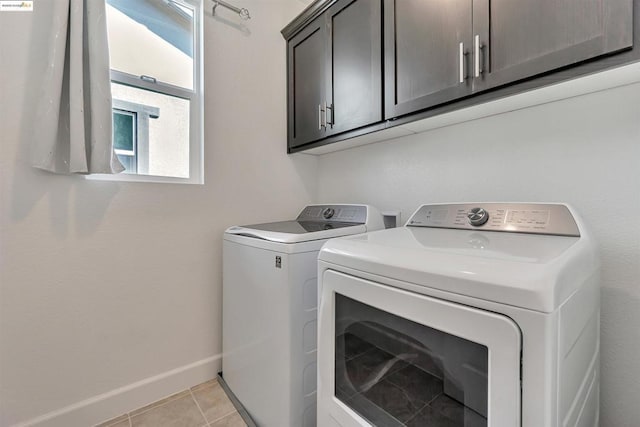 laundry area featuring washer and dryer, cabinets, and light tile patterned floors