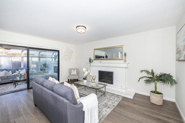 living room with dark hardwood / wood-style flooring and a brick fireplace