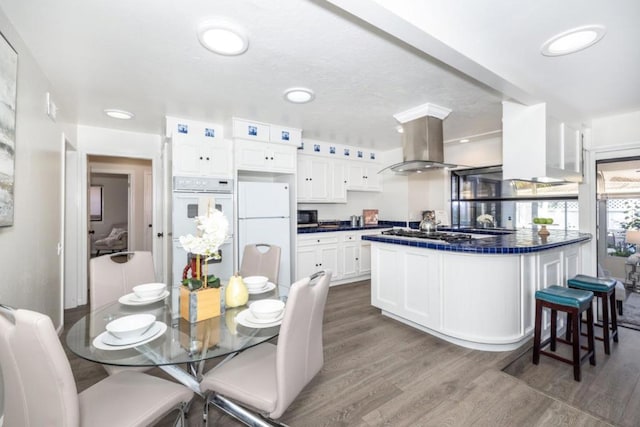 kitchen with white cabinetry, white appliances, island range hood, and wood-type flooring