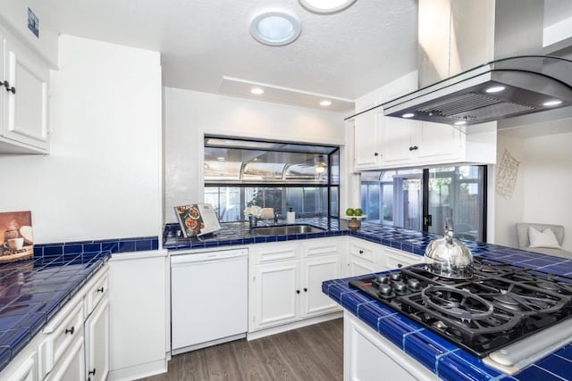 kitchen featuring white cabinetry, island range hood, gas cooktop, tile counters, and dishwasher